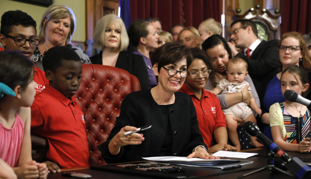 Iowa Gov. Kim Reynolds, center, signs a six-week abortion ban bill into law during a ceremony in her formal office on Friday in Des Moines, Iowa. The bill gives Iowa the strictest abortion restrictions in the nation, setting the state up for a lengthy court challenge.