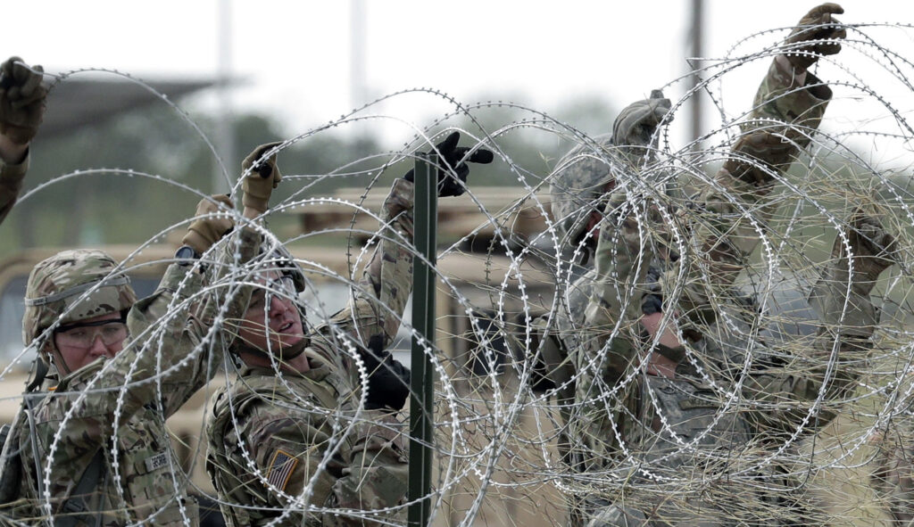 Members of the U.S. Army build a razor wire fence around area for tents near the U.S.-Mexico International bridge, Saturday, Nov. 3, 2018, in Donna, Texas. 