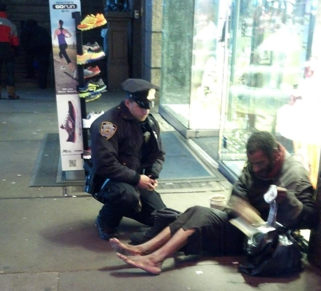   FILE- This file photo provided by Jennifer Foster from Nov. 14, 2012, shows New York City Police Officer Larry DePrimo presenting a barefoot homeless man in New York's Time Square with boots . (AP Photo)