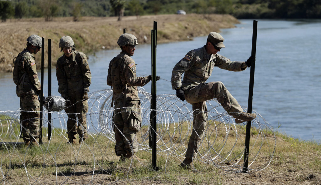 Members of the U.S. military install multiple tiers of concertina wire along the banks of the Rio Grande near the Juarez-Lincoln Bridge at the U.S.-Mexico border, Friday, Nov. 16, 2018, in Laredo, Texas.