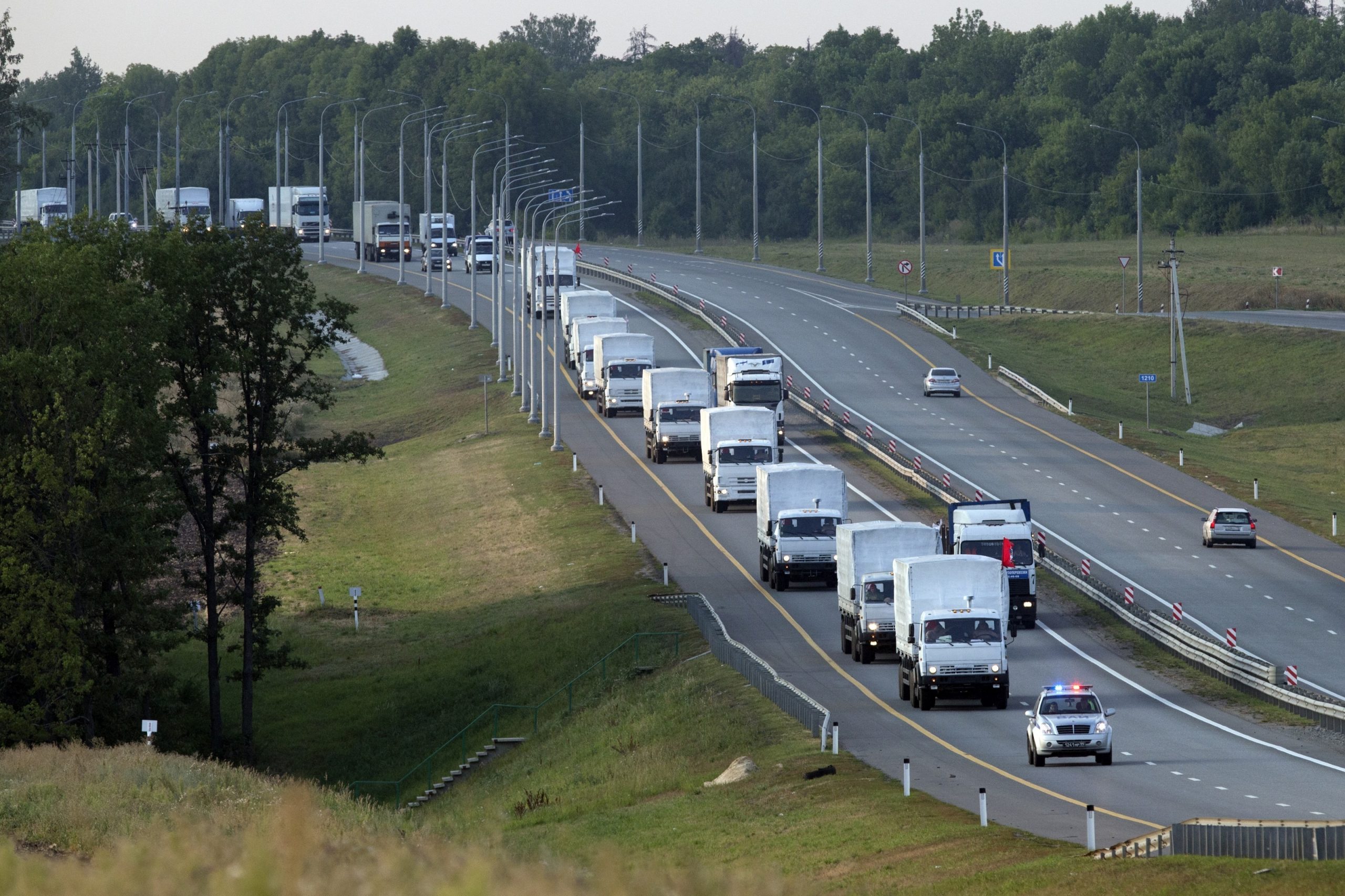A convoy of white trucks carrying humanitarian aid passes along a highway in the Voronezh region of Russia, Tuesday, Aug. 12, 2014. (AP Photo/Pavel Golovkin)