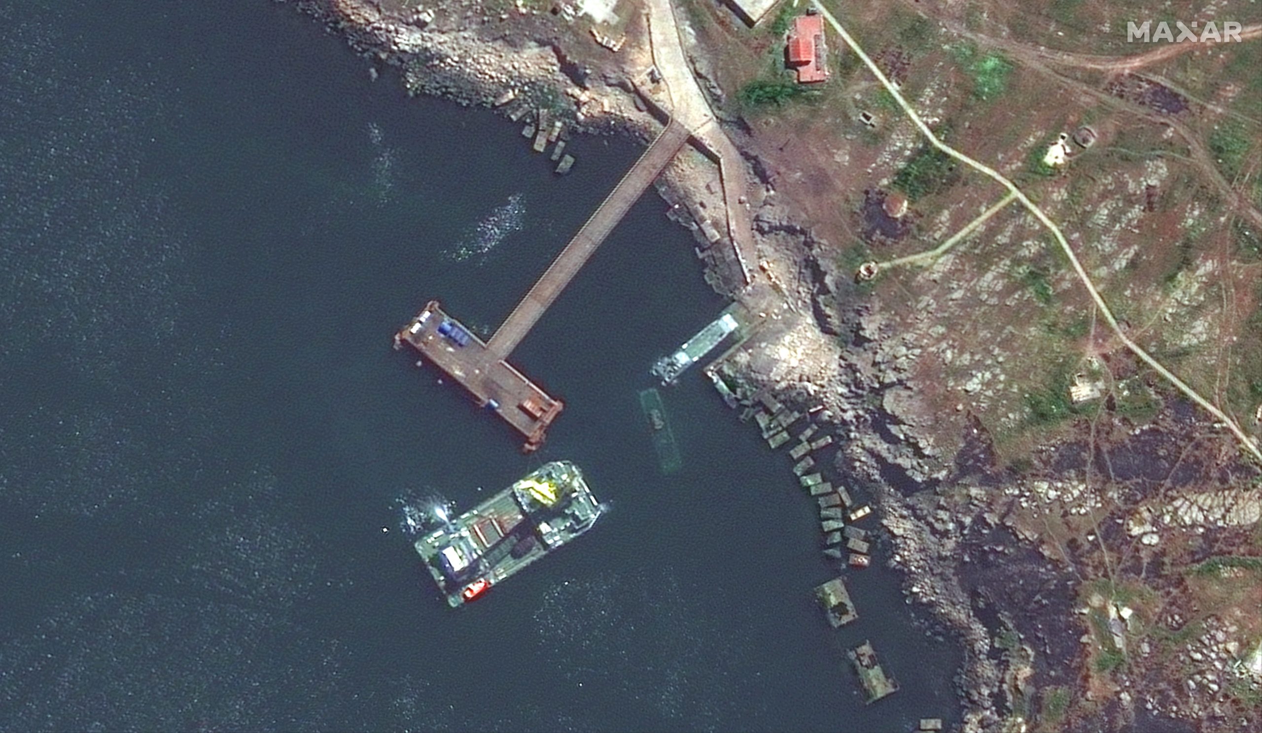 This image shows a closer view of a barge, a landing craft, and a sunken ship off Snake Island.