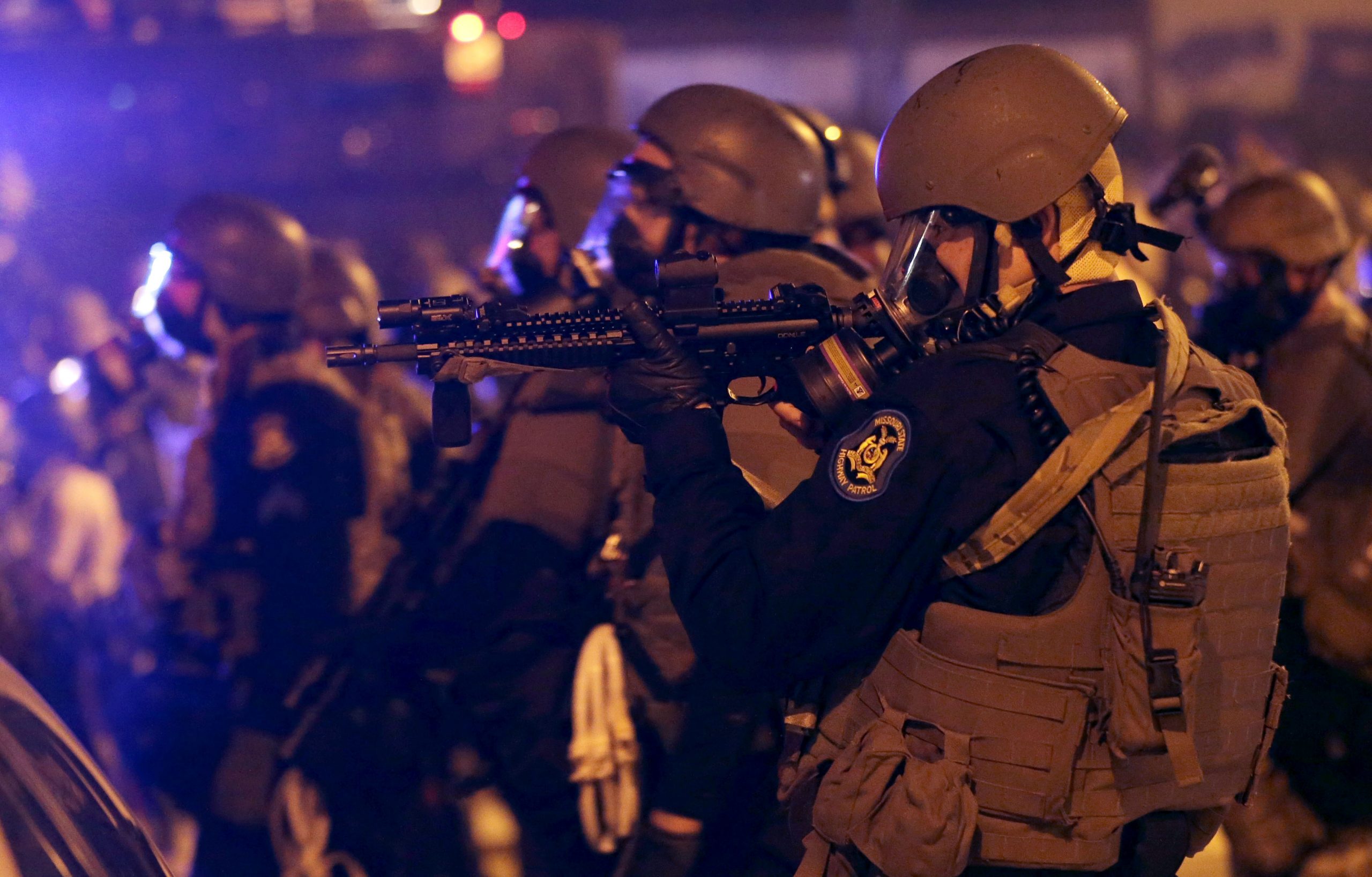 Police advance after tear gas was used to disperse a crowd Sunday, Aug. 17, 2014, during a protest for Michael Brown, who was killed by a police officer last Saturday in Ferguson, Mo. (AP Photo/Charlie Riedel)