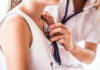 Unrecognizable young female doctor examining a small girl with stethoscope in her office. Close up.